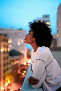 black woman overlooking city lights from balcony